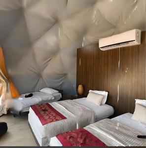 a bedroom with two beds and a ceiling with a projector at Rum Green Camp in Wadi Rum