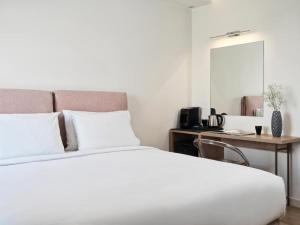 a bedroom with a white bed with a desk and a mirror at NLH Mati Seafront - Neighborhood Lifestyle Hotels in Mati