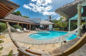 a hammock in front of a house with a swimming pool at Casa De Campo Gold Villa Vip in San Rafael del Yuma
