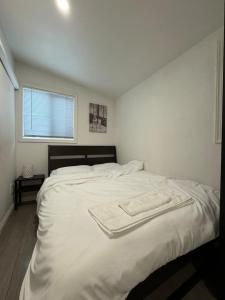 a white bed in a bedroom with a window at Guest House in West Covina