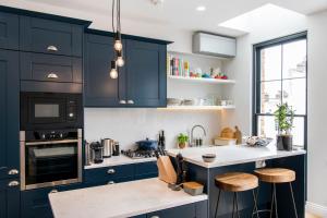 una cocina con armarios azul marino y encimeras blancas en Delightful Notting Hill 2 bed House with garden, en Londres