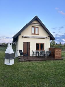 ein Haus mit einer Terrasse mit Stühlen und einem Grill in der Unterkunft Leszczynowe Zacisze in Wiele
