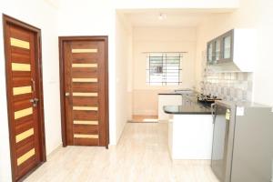 a kitchen with white walls and a wooden door at HSR Parkside by Newstays in Bangalore