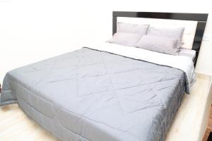 ein großes Bett mit einer grauen Bettdecke und Kissen in der Unterkunft HSR Parkside by Newstays in Bangalore