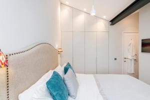 1 dormitorio con cama blanca y almohadas azules en Delightful Notting Hill 2 bed House with garden, en Londres