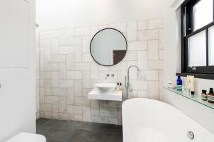 Baño blanco con lavabo y espejo en Delightful Notting Hill 2 bed House with garden, en Londres