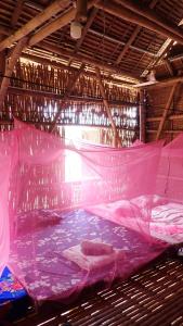 um quarto amplo com uma cama rosa e uma rede em OBT -The Corn Bungalow 