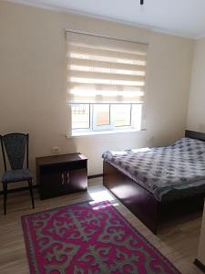 1 dormitorio con 1 cama, 1 silla y 1 ventana en Uz-Anar Guest House, en Kochkorka