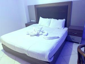 Una cama con sábanas blancas y toallas. en Cecelia Hotel Suites Hurghada, en Hurghada
