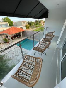 einen Balkon mit 3 Stühlen und einem Pool in der Unterkunft Villa 1 in Santo Domingo