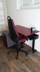un escritorio con una silla roja junto a un escritorio con un cajón en "Riposo" von Samstag zu Samstag buchbar, en Bellerive
