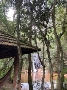 a bridge over a river with a waterfall in the background at Chalé Sonho Diniz 2 in Monte Verde