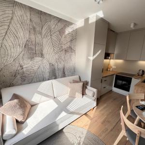 a living room with a white couch and a kitchen at Apartament Przytulny in Zamość