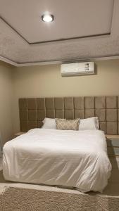 een slaapkamer met een groot wit bed met een hoofdeinde bij فندق منيف بن طالب in Khamis Mushayt