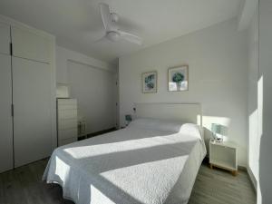 biała sypialnia z łóżkiem i wentylatorem sufitowym w obiekcie Apartamento Playa vistas 2 w mieście Los Cristianos