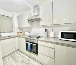 een witte keuken met een fornuis en een magnetron bij Modern Gem Apartment in Deptford with parking in Londen