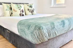 een bed met een blauwe deken en kussens erop bij Modern Gem Apartment in Deptford with parking in Londen