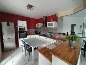 a kitchen with red walls and a table with chairs at villa Soleil 3chambres piscine in Lagorce