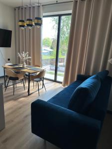 a living room with a blue couch and a table at Apartament DELUX ROZTOCZE in Tomaszów Lubelski