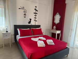 a bedroom with a red bed with towels on it at Aristos Apartments & Suites in Stalos