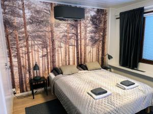 a bedroom with a bed with a forest mural on the wall at Pine Sky Apartments in Ivalo