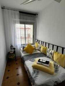 - un salon avec 2 lits et des oreillers jaunes dans l'établissement Apartamento Veracruz 200 m de la Playa, à Gandía