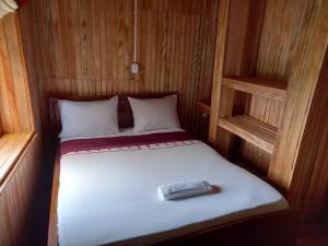 ein kleines Bett in einem Holzzimmer mit weißem Bettlaken in der Unterkunft KSW BASE NAUTIQUE Isonalambo in Kribi