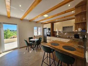 a kitchen with a wooden table and green chairs at House Konavle in Gruda