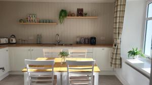 una cucina con tavolo in legno e sedie bianche di An Cnoc Bed & Breakfast a Staffin