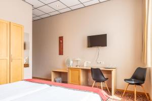 - une chambre avec 2 chaises, un bureau et une télévision dans l'établissement Hotel - Brasserie Ingredi, à Brée