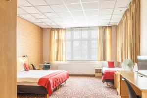 Cette chambre comprend deux lits et une baignoire. dans l'établissement Hotel - Brasserie Ingredi, à Brée