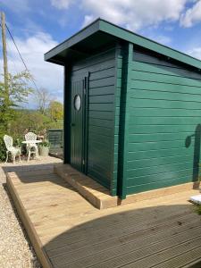 a green shed on a wooden deck with a table at Corner House in Cudworth