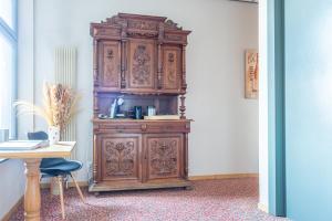 a large wooden cabinet in a room with a table at Hotel - Brasserie Ingredi in Bree