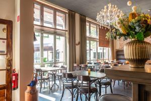 un restaurant avec des tables, des chaises et un vase de fleurs dans l'établissement Hotel - Brasserie Ingredi, à Brée