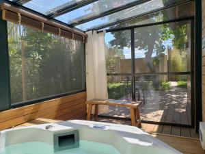 a bathroom with a tub and a large window at Le mazet des amants, cabane en bois avec jacuzzi privatif in Avignon