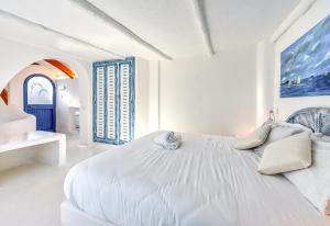 a white bedroom with a large white bed and two windows at Villa Ravino Aparthotel in Ischia