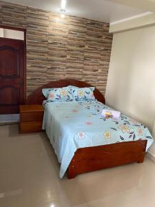 a bedroom with a large bed with a wooden headboard at HOSTAL LOS NOGALES in Aguaytía
