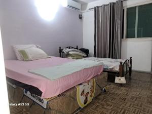 two twin beds in a room with a window at Yulendo Backpackers in Beira