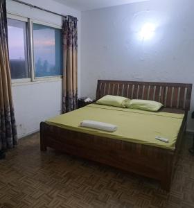 a bedroom with a bed with a green sheets and a window at Yulendo Backpackers in Beira