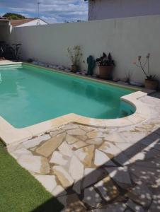 una piscina en un patio con una pared blanca en Grande villa avec piscine et clim proche de la mer, en Marsillargues