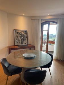 comedor con mesa, sillas y ventana en Quatre Saisons Residence, en Campos do Jordão