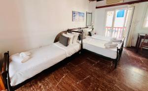 2 łóżka pojedyncze w pokoju z drewnianą podłogą w obiekcie Studio Eleni w mieście Mykonos
