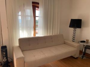 un sofá blanco en una sala de estar con ventana en Quatre Saisons Residence, en Campos do Jordão