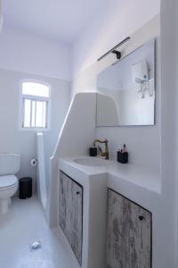 a white bathroom with a sink and a toilet at Summer House in Porto Heli