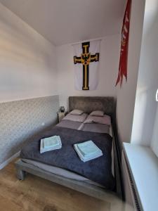 a bedroom with a bed with a cross on the wall at Apartamenty Zakonne "Apartament Rycerza" in Malbork
