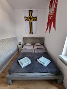 a bed in a room with a cross on the wall at Apartamenty Zakonne "Apartament Rycerza" in Malbork