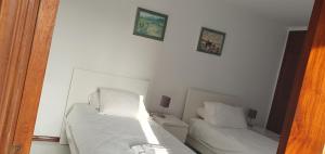 a white bedroom with two beds and a mirror at Penthouse with panoramic view in Vilamoura