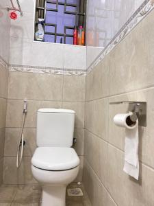 a bathroom with a toilet and a roll of toilet paper at Modest Spacious Apartment in Kampala +23 photos