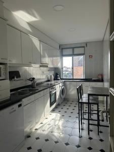 a kitchen with white cabinets and a table and a stove at Seventy in Póvoa de Varzim