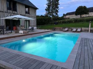 une piscine avec une terrasse et une maison dans l'établissement La Boisselière à Bonnebosq, à Bonnebosq
